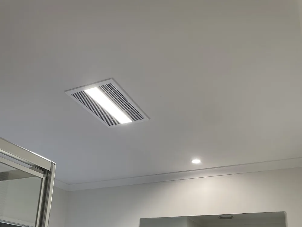 Bathroom ceiling with a new exhaust unit and downlight above the vanity mirror