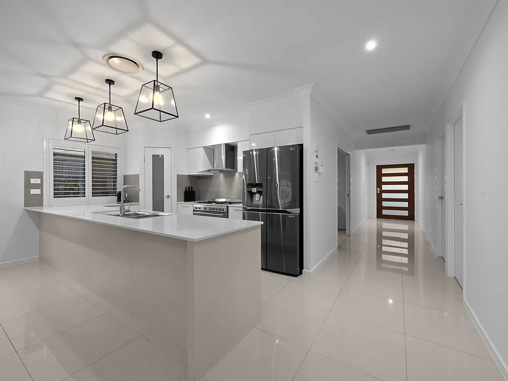 Three black cage pendant lights hung over a white kitchen island