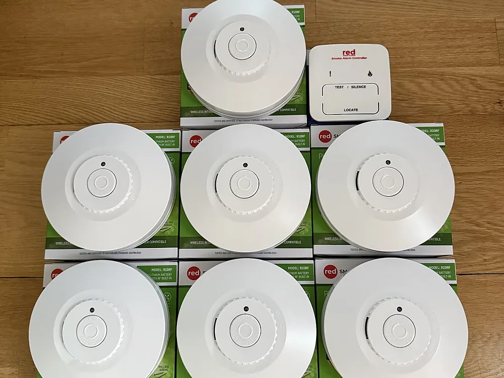 Stack of new photoelectric smoke alarms ready for installation