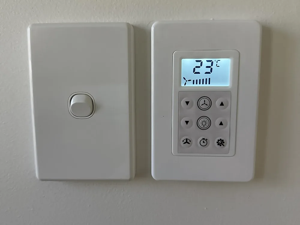 New white light switch plate installed beside an air conditioner controller