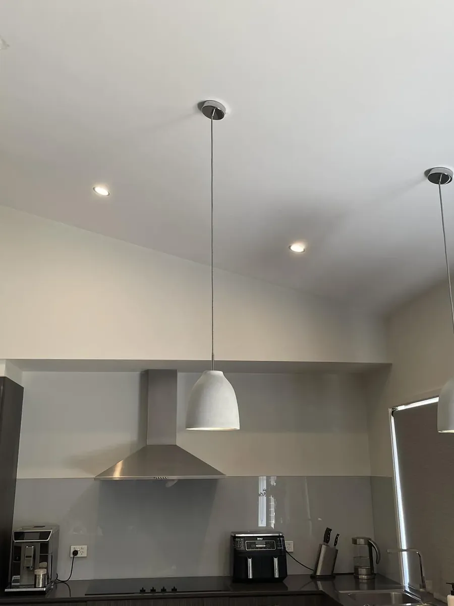 Three white dome pendants hanging from a raked kitchen ceiling
