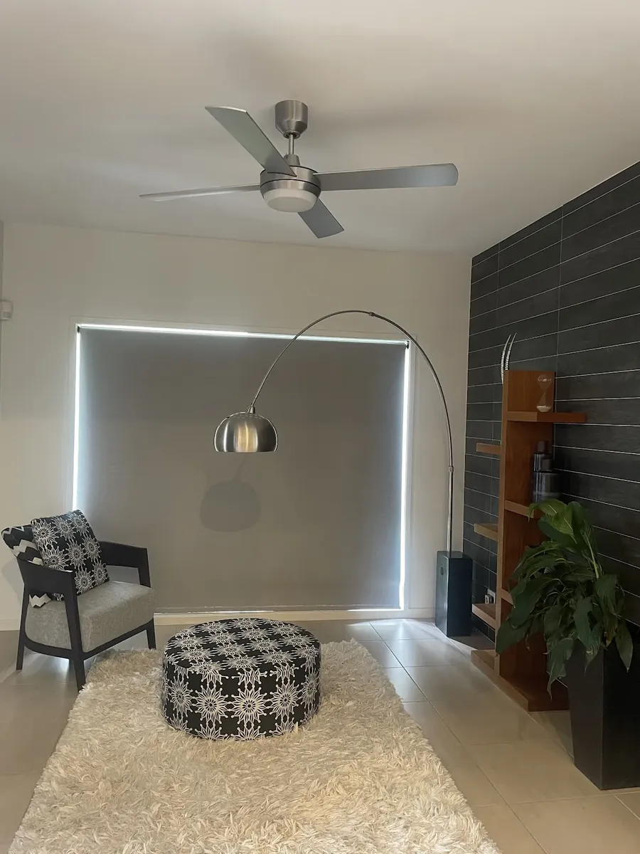 Brushed steel ceiling fan in a living room with a feature wall