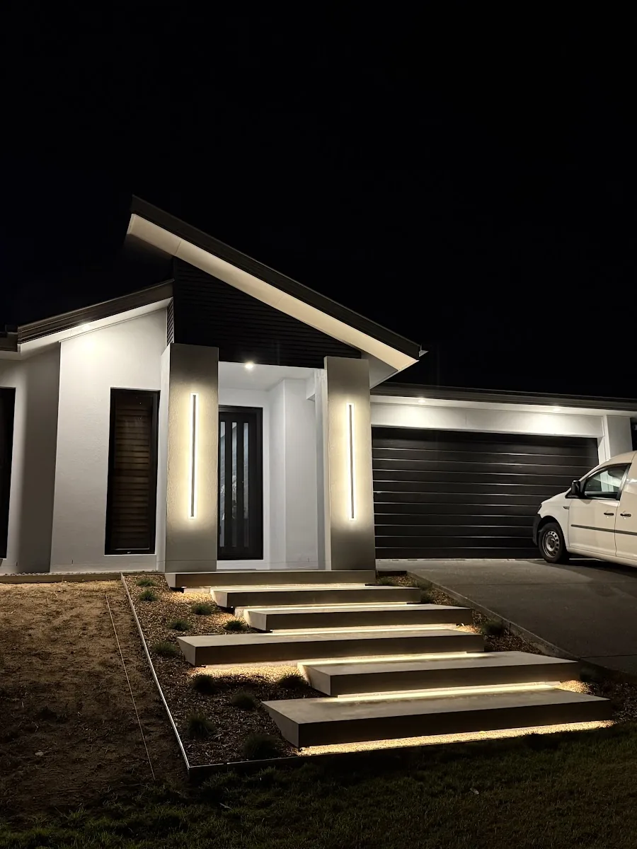 Modern home at night with glowing floating step lights and vertical wall lights by the front door