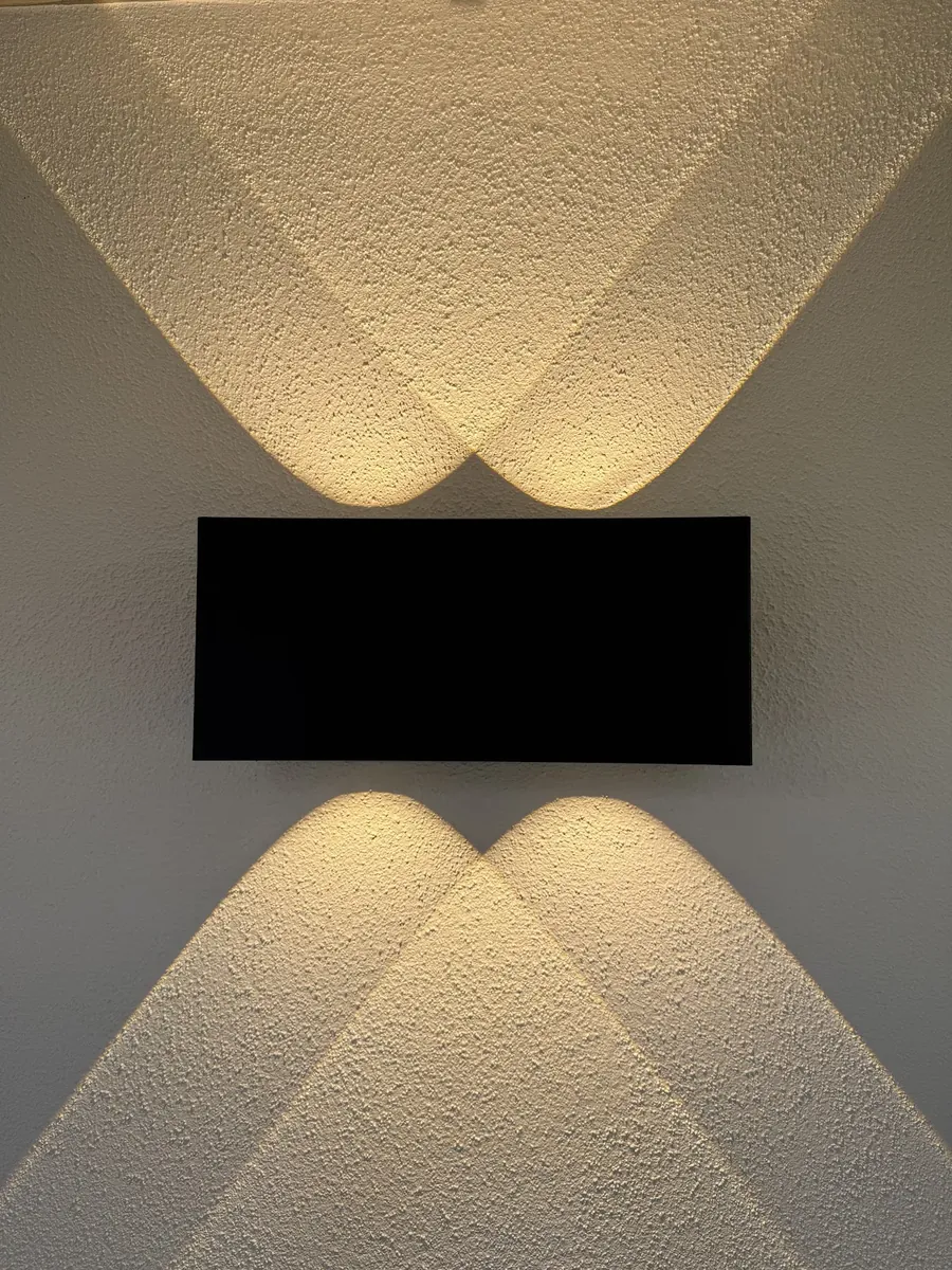 Black up and down wall light washing warm light over a textured wall